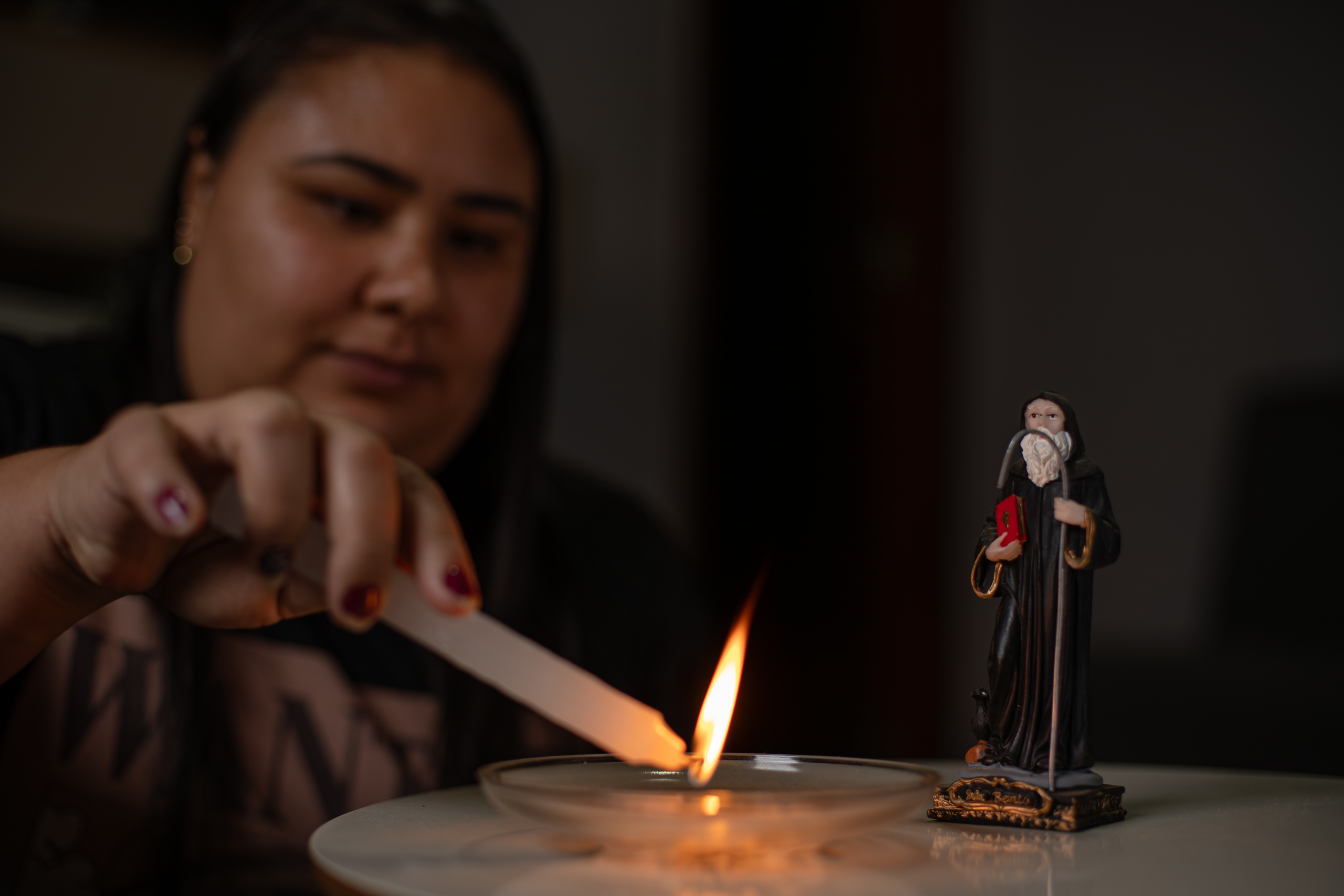 Samara Quintão acende uma vela para São Bento, padroeiro de Bento Rodrigues. 