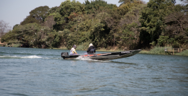 Comunidades pesqueiras: barco com dois pescadores navega pelas águas da Represa de Três Marias