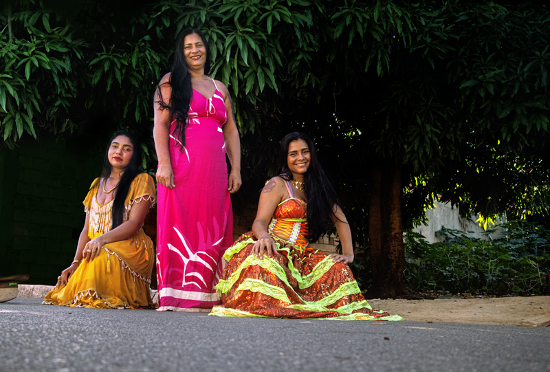 Três mulheres do povo Calon com vestidos típicos de colorido vibrante.