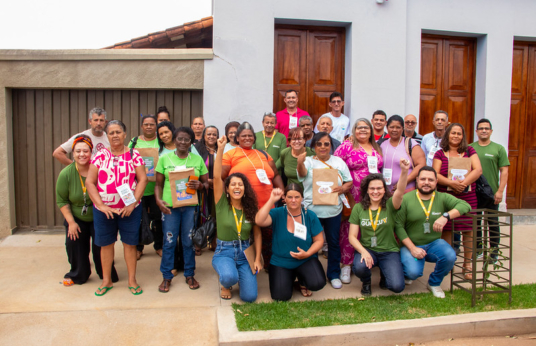 Grupo de pessoas, algumas uniformizadas, posando para uma fotografia do grupo.