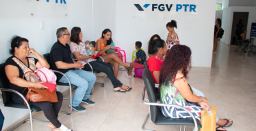 Pessoas aguardando atendimento em cadeiras dentro do posto de atendimento da FGV