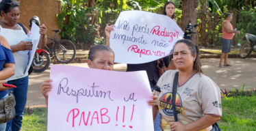 Várias mulheres de pé em espaço aberto. Em primeiro plano, uma delas está com o cartaz escrito à mão "Respeitem a PNAB". No fundo, outra segura o cartaz "Não pode Reduzir enquanto não Reparar".