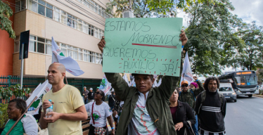 Em manifestação na rua, homem carrega cartaz escrito "Garantia dos 'ATI' até a reparação dos danos"
