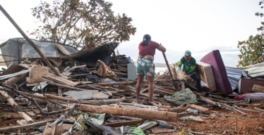 Mulher e homem buscam itens em meio a destroços de construção