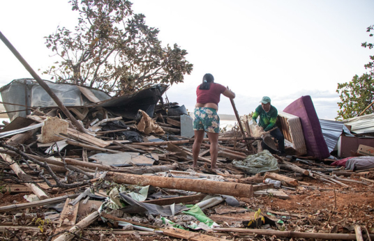 Mulher e homem buscam itens em meio a destroços de construção