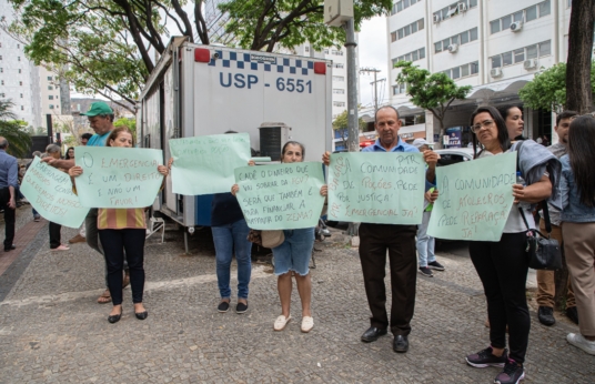Dois homens e quatro mulheres seguram cartazes com pedidos de direitos como o auxílio emergencial e a reparação.