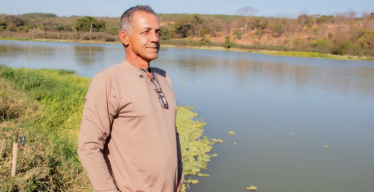 Homem à beira de curso d'água olha para o horizonte