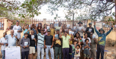 Várias pessoas posando para a foto com expressão de comemoração segurando material impresso e próximas a flipchart escrito à mão: "Lançamento do Protocolo de Consulta — Ribeirinhos do São Francisco".