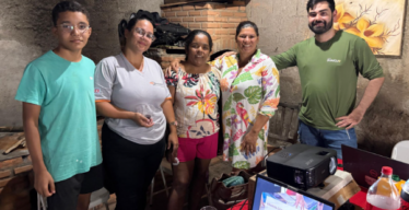 Cinco pessoas, uma delas com o unforme do Instituto Guaicuy, posam para foto em ambiente interno. No local também há um computador e um projetor.