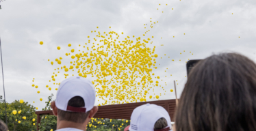 Pessoas de boné observam os balões amarelos no céu em homenagem às vítimas do rompimento da barragem da Vale em Brumadinho (acervo Guaicuy).