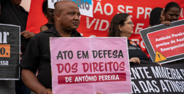 Foto de homem segurando placa em manifestação com os dizeres "Ato em defesa dos direitos de Antônio Pereira"