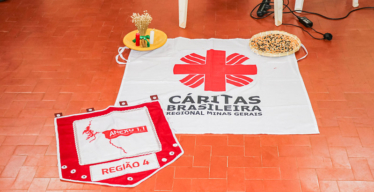 Bandeira da Cáritas Brasileira e estandarte do Anexo 1.1 no chão