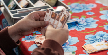 Mão segurando notas de moeda social no banco comunitário da Catira do Cerrado